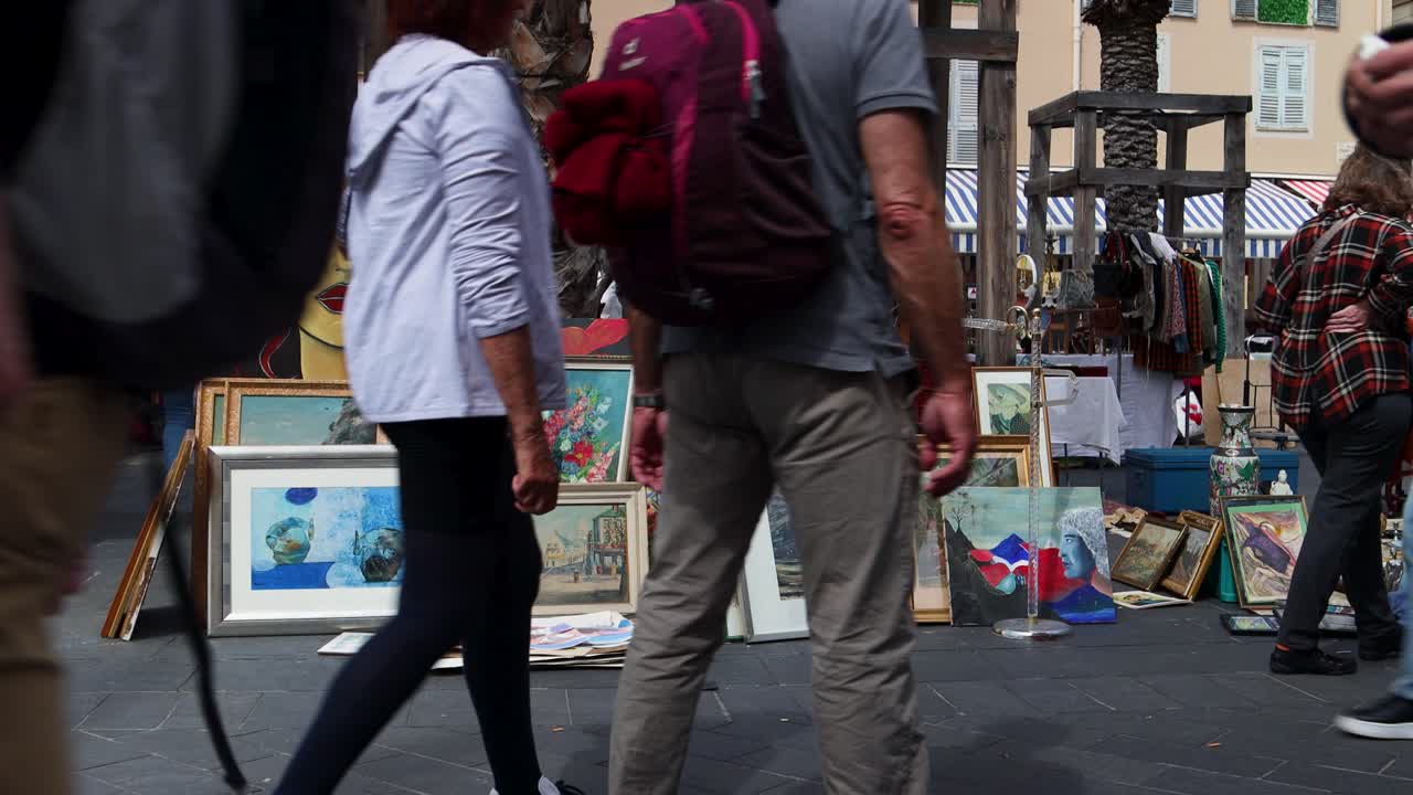 Art market at Cours Saleya in Nice with colorful paintings and people browsing