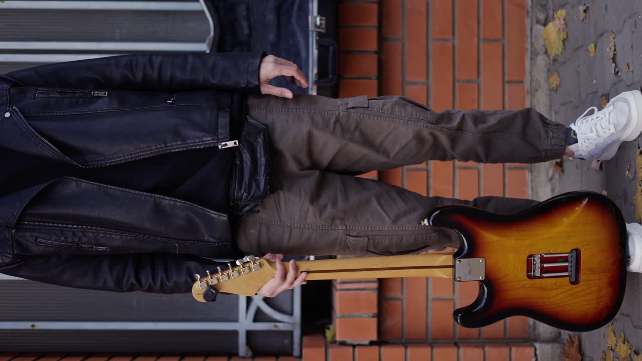 Man smiling on the street and carrying a guitar