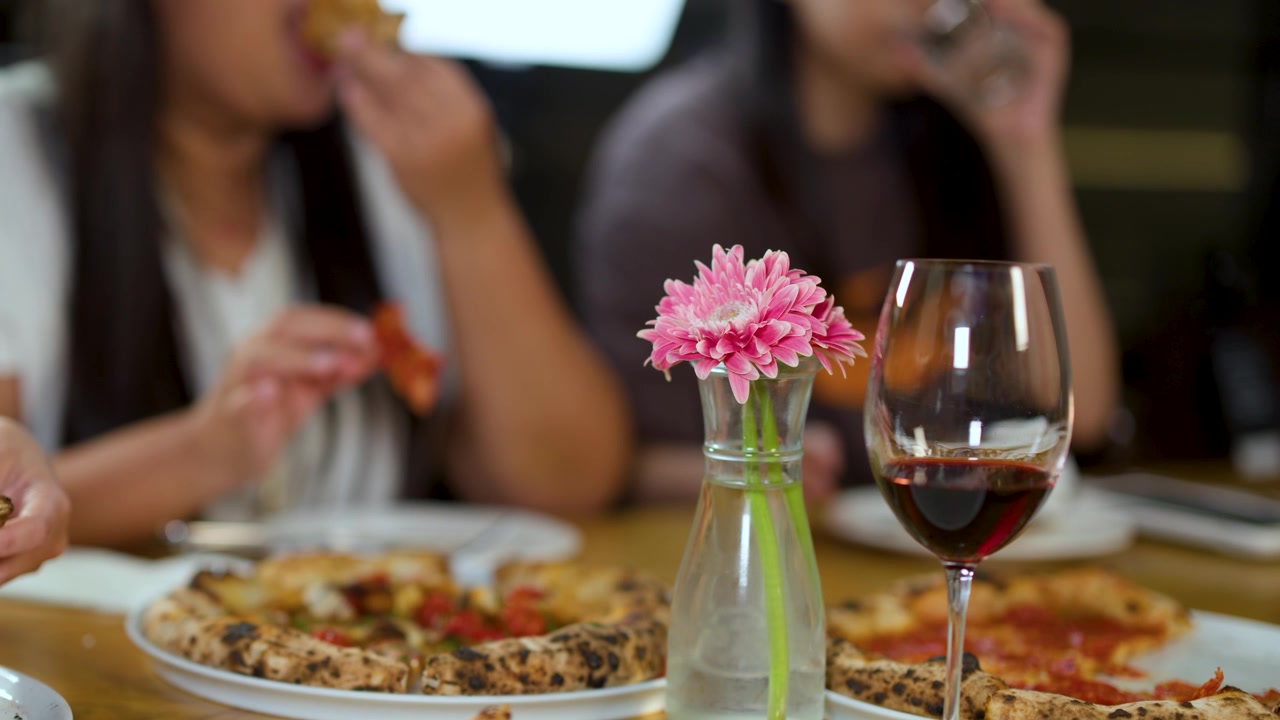 Amici che mangiano pizza e bevono vino a un tavolo di ristorante