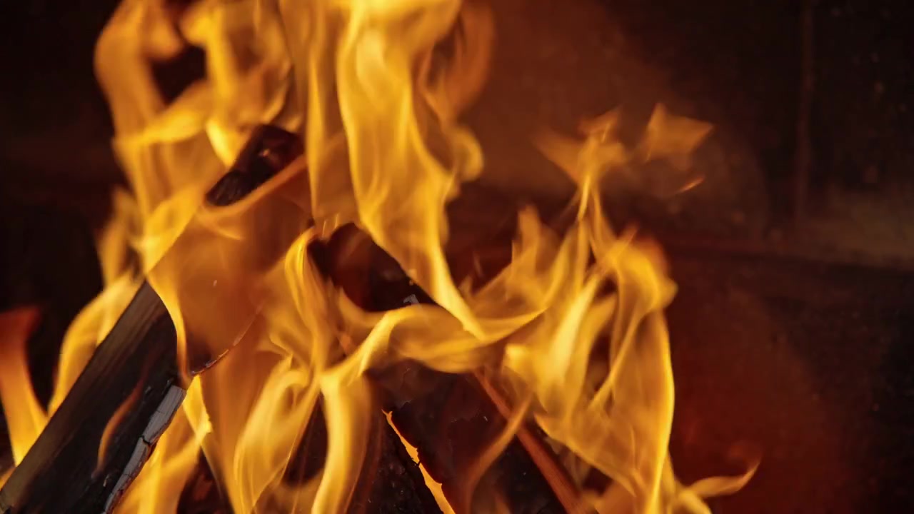 Nærbilde av lyse oransje og gule flammer som brenner vedkubber