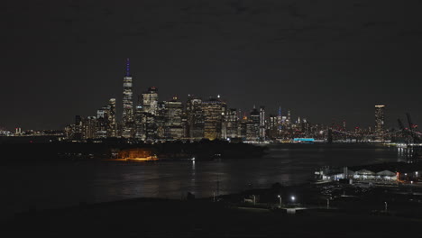 NYC-New-York-Luftaufnahme-V280-Tiefflug-über-Red-Hook-Brooklyn-Mit-Aufnahme-Von-Governors-Island-Und-Der-Beleuchteten-Innenstadtlandschaft-Von-Lower-Manhattan-Bei-Nacht-–-Aufgenommen-Mit-Inspire-3-8k-–-September-2023