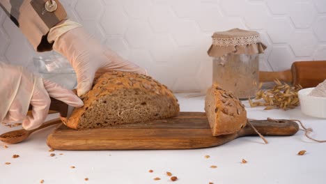 the chef cuts homemade bread loaf into slices. sourdough on the background