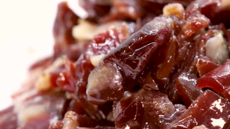 fatty prosciutto pieces rotating on white surface, macro shot in 4k