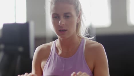 Front-view-athletic-Caucasian-woman-exercising-on-a-rowing-machine