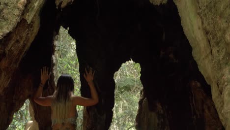 Mujer-Tocando-El-Hueco-Del-árbol-De-Los-Deseos---Interior-De-La-Costa-Dorada,-Queensland---Inclinación-Hacia-Abajo-Revelada