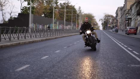 Stylish-man-with-orange-iroquois-rides-a-bike-by-city-street