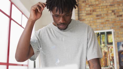 african american male painter holding brush and thinking in artist studio