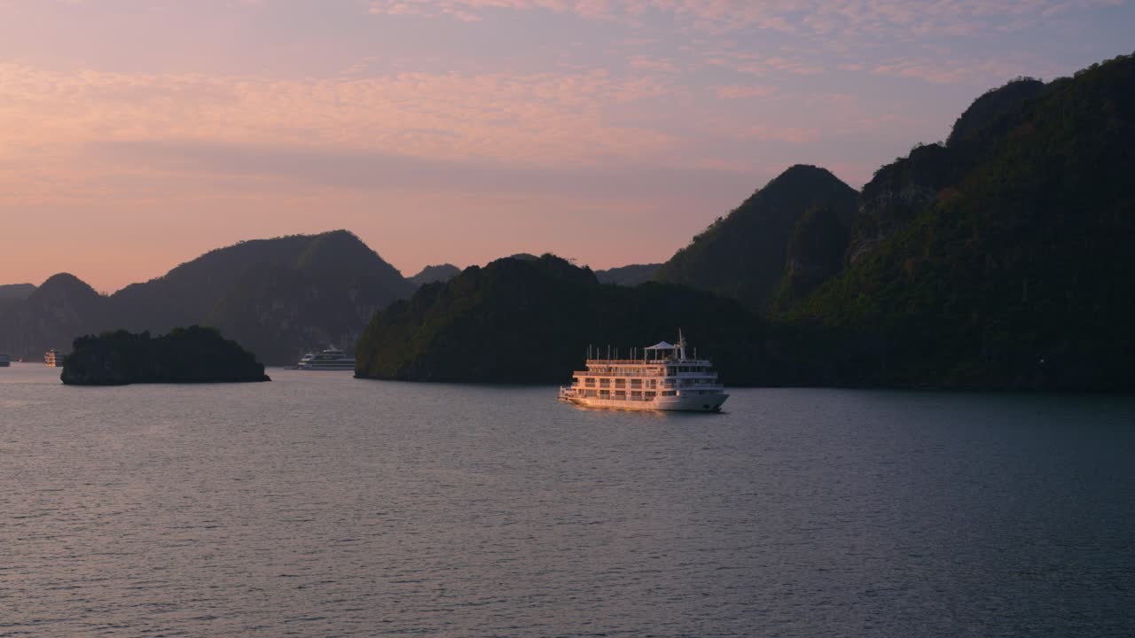 Cruise ship slowly cruising at Halong Bay during sunset, Vietnam - high angle pan aerial