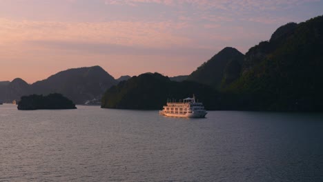 cruise ship slowly cruising at halong bay during sunset, vietnam - high angle pan aerial