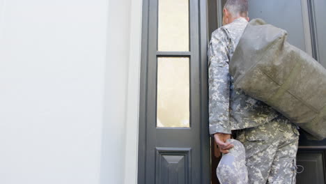 caucasian male soldier in uniform returning home walking into house