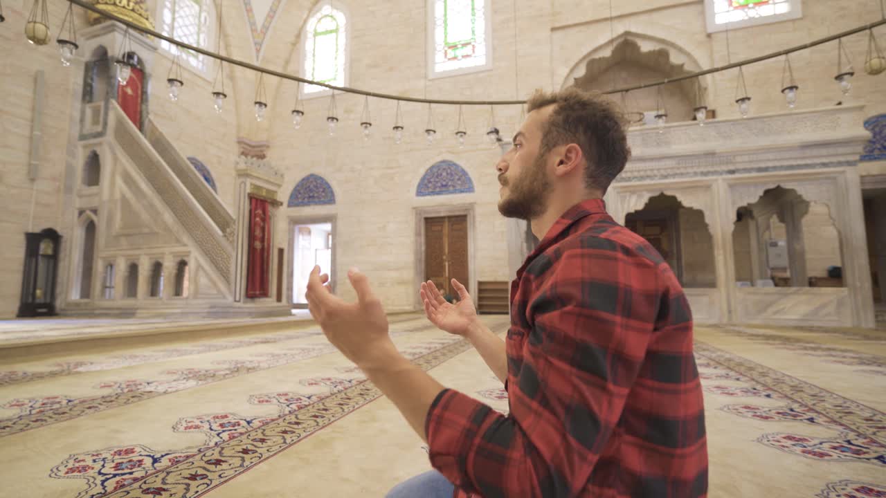 역사적인 모스크에서 기도하는 젊은 무슬림 남자.