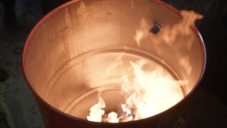 Homeless-people-warming-near-fire-barrel-standing-at-night-in-winter