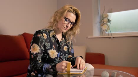 woman writing at home wearing floral shirt