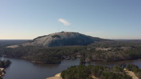 Disparo-Aéreo-De-Un-Dron-Cayendo-Lentamente-Mientras-Mira-Hacia-El-Lado-Norte-De-La-Montaña-De-Piedra-En-El-Parque-De-La-Montaña-De-Piedra-Con-El-Monumento-Confederado-A-Un-Lado-Y-Góndolas-Subiendo-Y-Bajando-La-Montaña