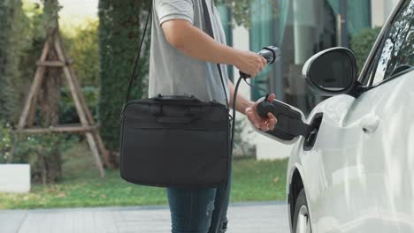 Progressive man unplugs the electric vehicle&#039;s charger at his residence.