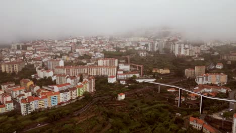 A-bird's-eye-perspective-of-Covilha-Village-showcases-a-tall-skyscraper,-a-suspended-bridge,-and-narrow-streets---2