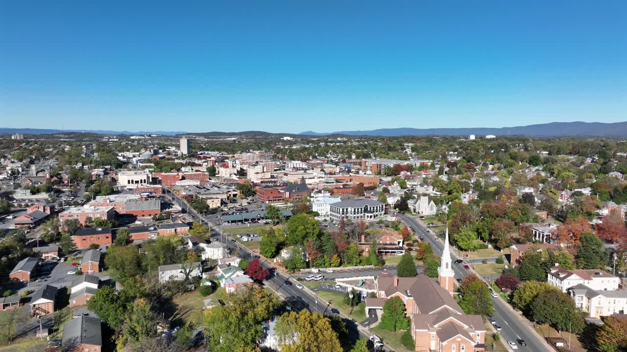 Incrocio stradale di una città americana durante una giornata soleggiata e alberi verdi. Ampia ripresa aerea. Zona residenziale di Harrisonburg e centro in secondo piano. Virginia, USA. Quartieri tranquilli e silenziosi. Biforcazione stradale
