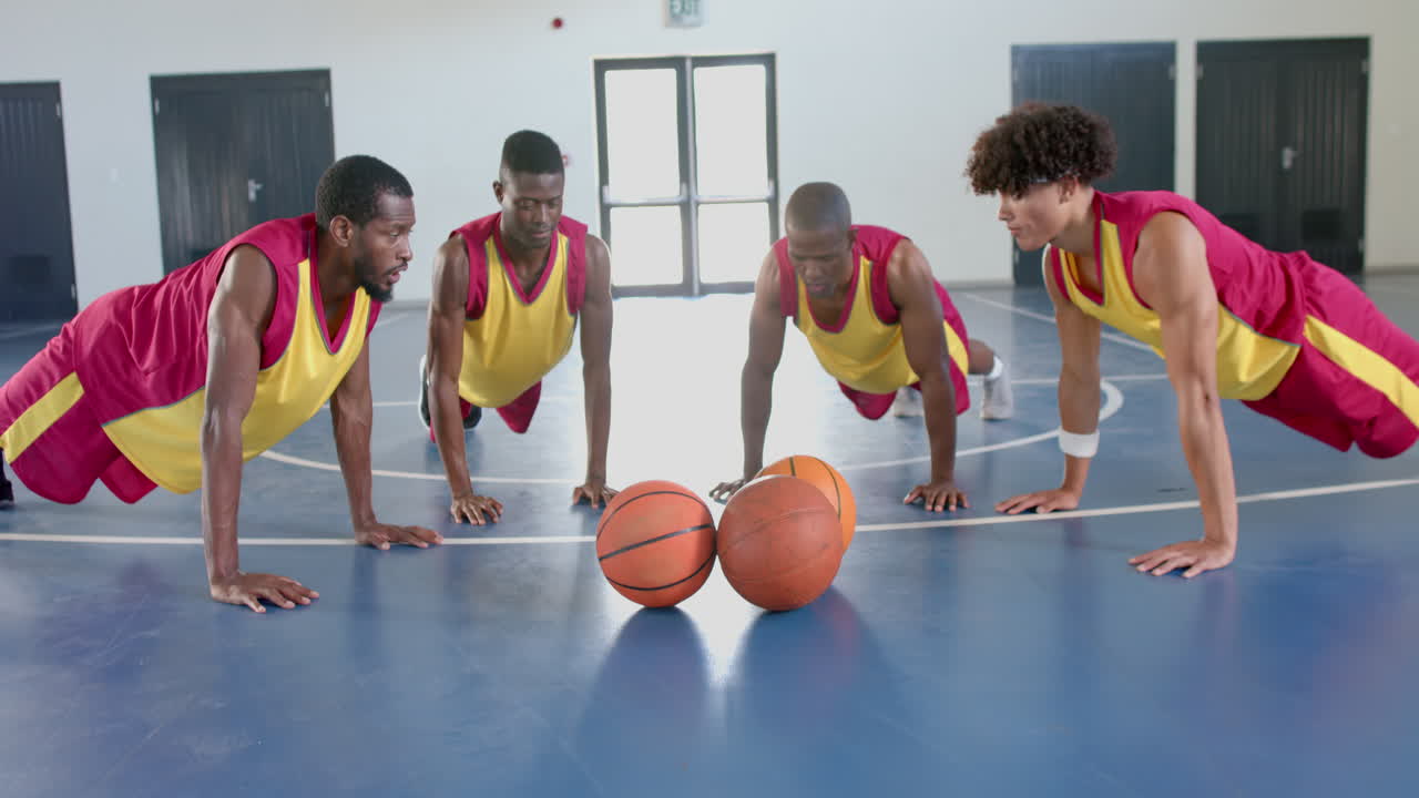 varios jugadores de baloncesto realizan flexiones en un gimnasio