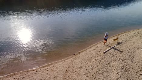 woman with her pet dog walking near river coast on a sunny day 4k