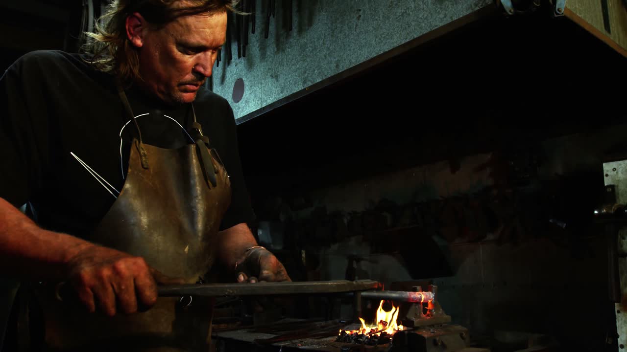 herrero trabajando en una barra de hierro
