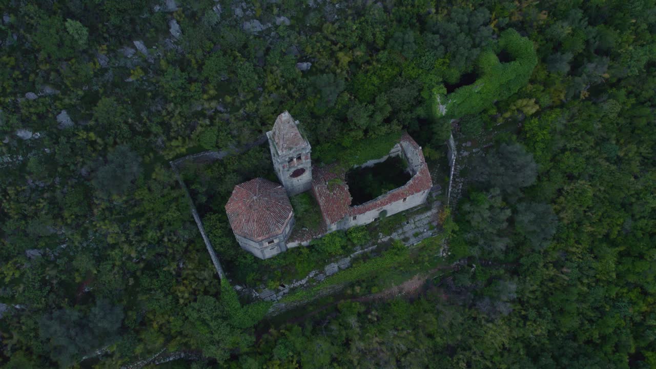 abajo de la iglesia en ruinas en la montaña verde exuberante durante el día en la bahía de kotor, aérea