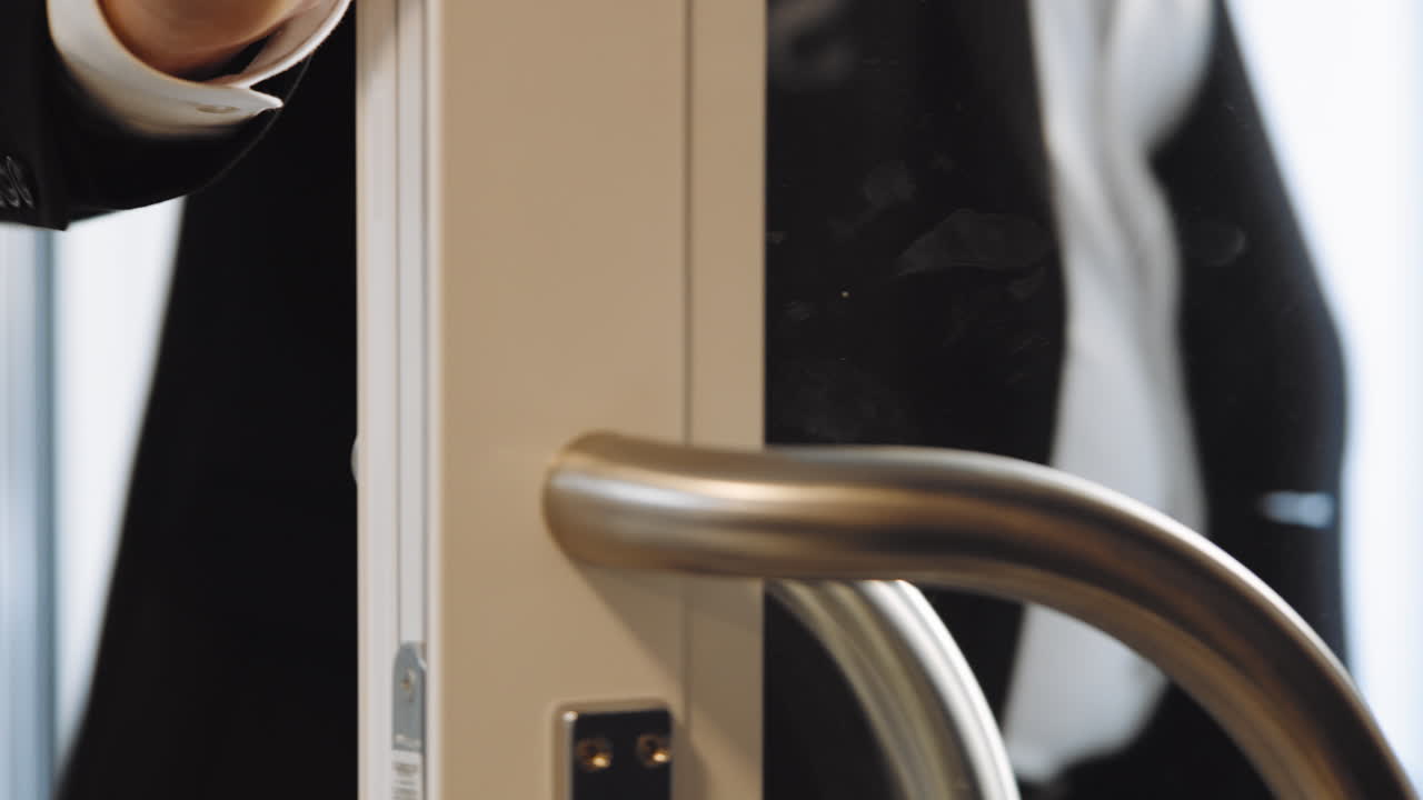 멋진 비싼 양복을 입은 남자가 문을 열고 집으로 걸어가 모험을 떠나 마지막으로 출구에서 나가며 유리 문 부동산 중개인 부동산 은행 은행 환영을 여는 손을 말합니다.