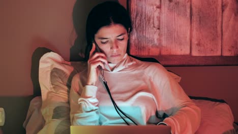 mujer joven multitarea con teléfono y portátil en la cama