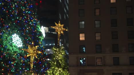 close up parallax of vancouver city very large and tall christmas tree lit up and glowing with other christmas decorations surrounded by the tall lit up buildings on a winter night in the dark