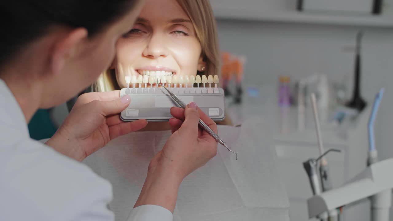 el dentista elige el color de los dientes de la paleta