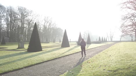 a girl is walking through the morning sunlight at the park