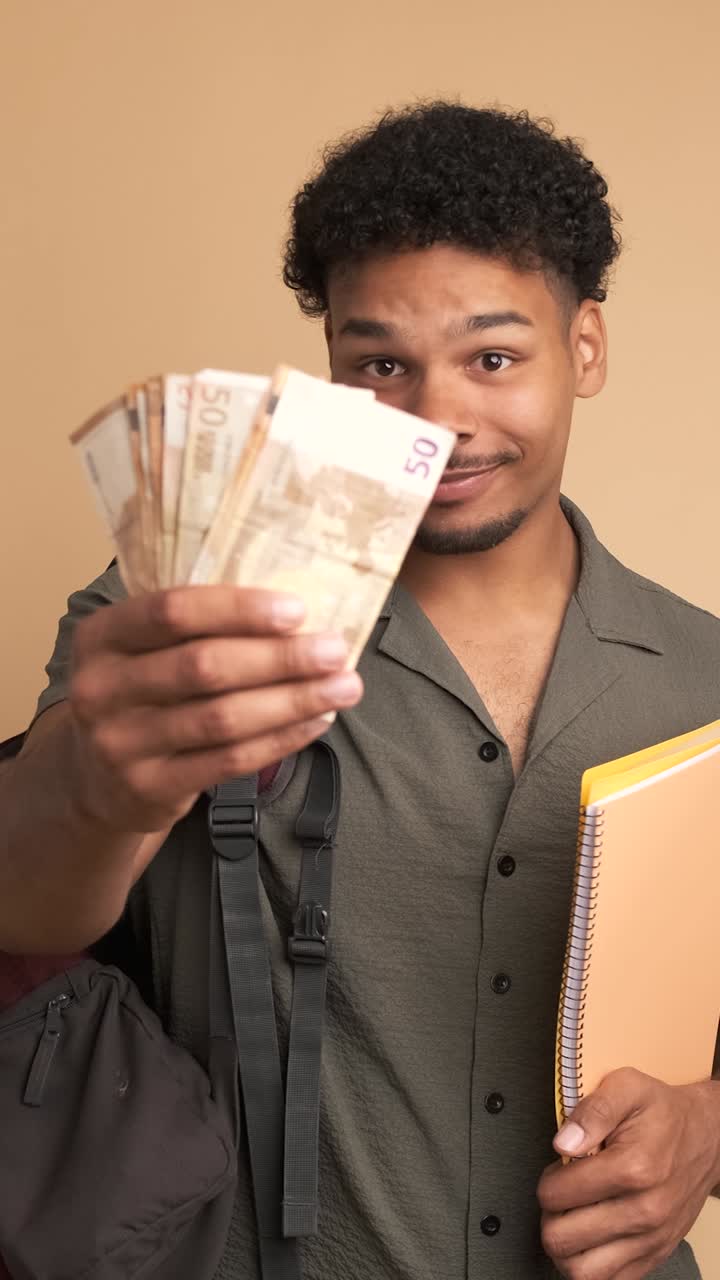Happy young male student displaying scholarship money in beige studio