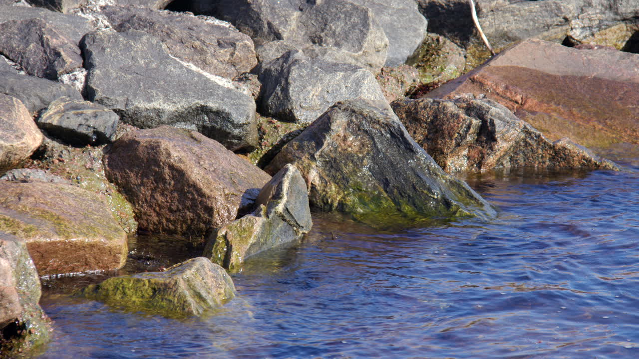 Waves gently lapping onto harbour rocks at Kristiansand
