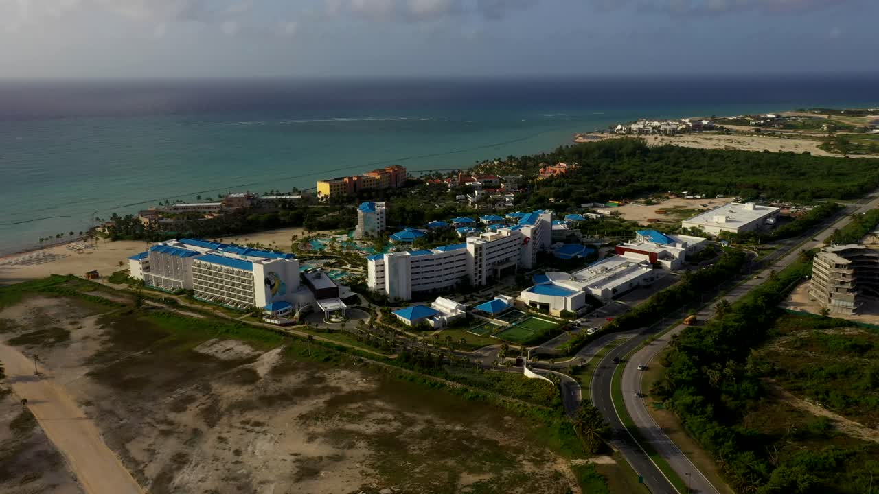 High aerial orbit of Margaritaville resort near shoreline with adjacent beachfront property in Cap Cana Dominican Republic