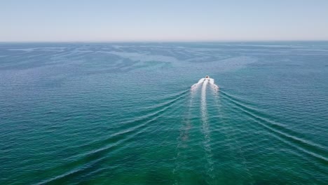 speedboat cuts through water, leaving frothy trail as it races towards horizon