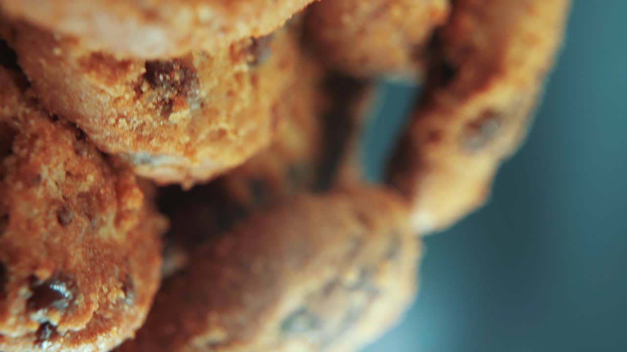 una toma cinematográfica macro vertical de un plato lleno de galletas de chocolate crujientes y jugosas, en un soporte giratorio, iluminación de estudio, cámara lenta, cámara suave, video 4k