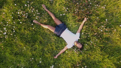 zoom out of a man lying and relaxing on the edge of a cliff of a rocky coastline