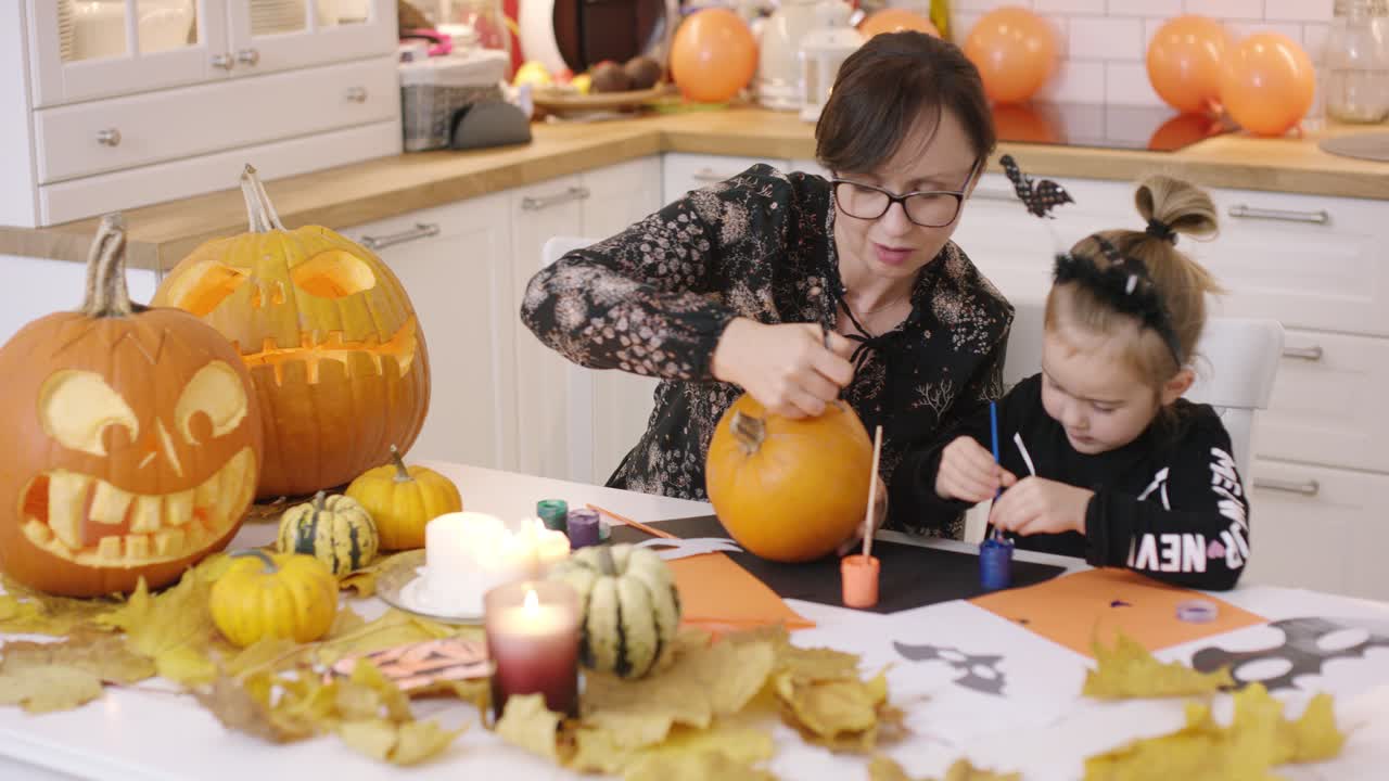 mujer y niña pintando cara en calabaza