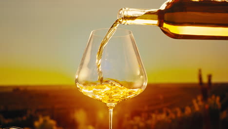orange or white wine bottle and glass against a sunset in a peaceful vineyard, pouring of ecological natural wine.