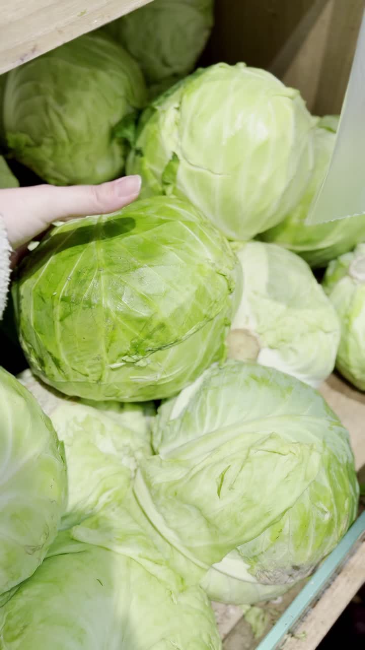 Woman buying cabbage at a grocery store