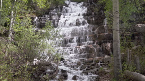 Beautiful-cascading-waterfall-surrounded-by-aspen-trees-in-Glacier-National-Park,-Montana