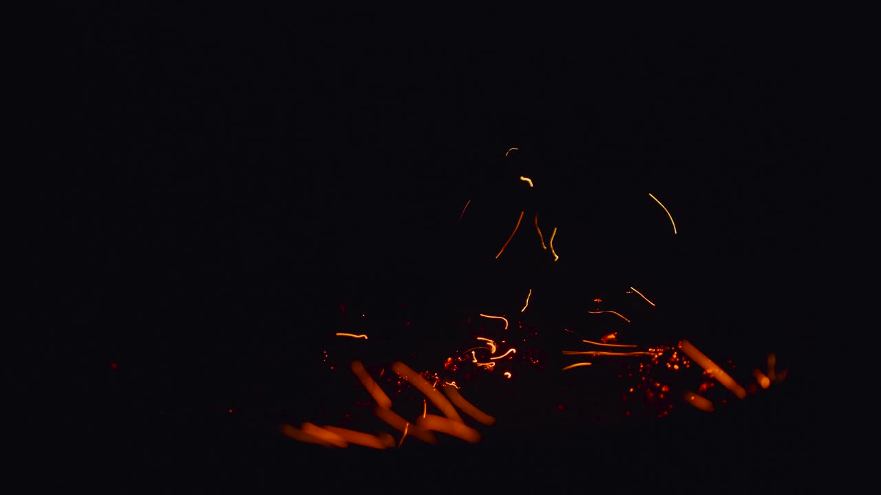 fogata ardiente. primer plano de chispas voladoras sobre un fondo negro. llamas de fuego y chispas