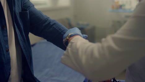 woman doctor putting cuff measuring blood pressure on old man arm close up.