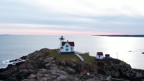 Close-Orbit-of-lighthouse-on-a-rocky-coastal-island-with-rippling-water-and-blue-sky-above