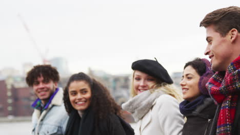 friends walking along south bank on winter visit to london