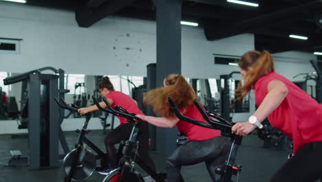 Healthy-Caucasian-group-of-women-exercising-workout-on-stationary-cycling-machine-bike-in-gym