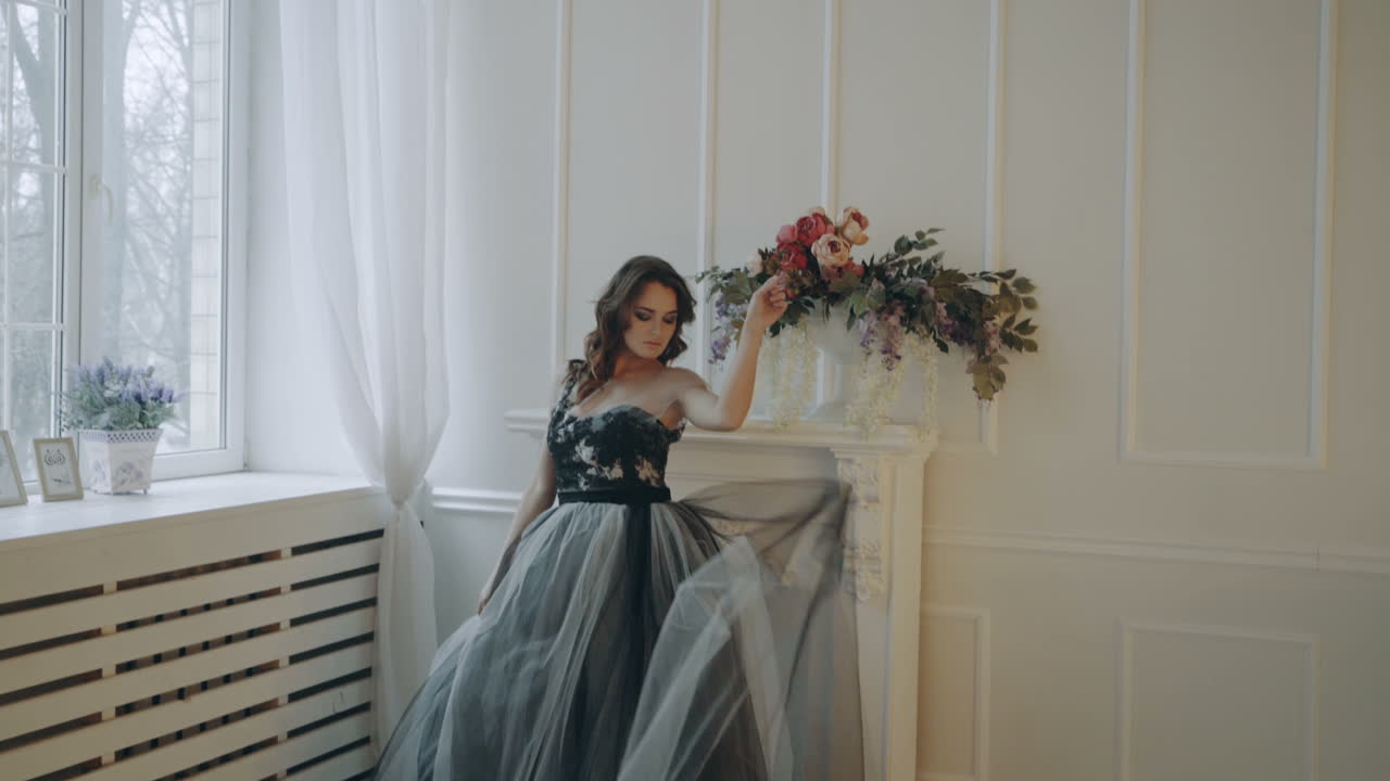 Girl in beautiful dress. Young woman in evening dress posing in decorated room in studio