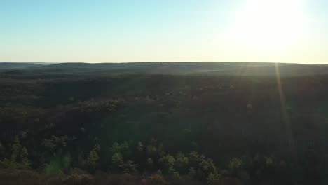 Drone-pullup-over-mountain-homes-and-forested-hills-at-winter-sunrise