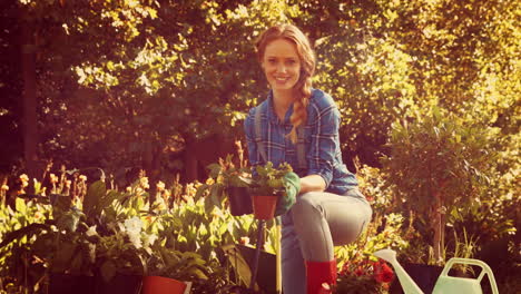 happy pretty gardener looking at camera and showing flower pot