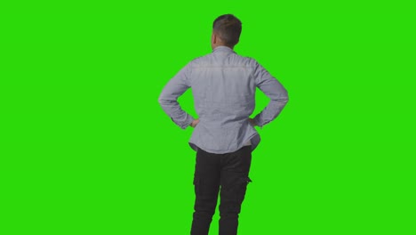 three quarter length studio rear view of casually dressed young man looking at green screen