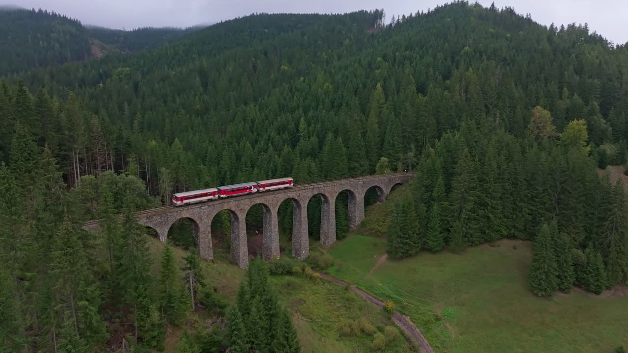 Vlak přejíždí Chmarošský viadukt hustým zeleným lesem, Telgárt, Slovensko